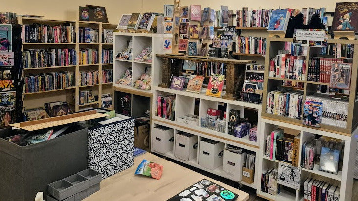Room with bookshelves filled with books and collectibles on a wooden floor.
